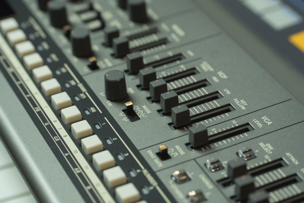 Detailed view of a music mixing console with various sliders and buttons in a studio setting.