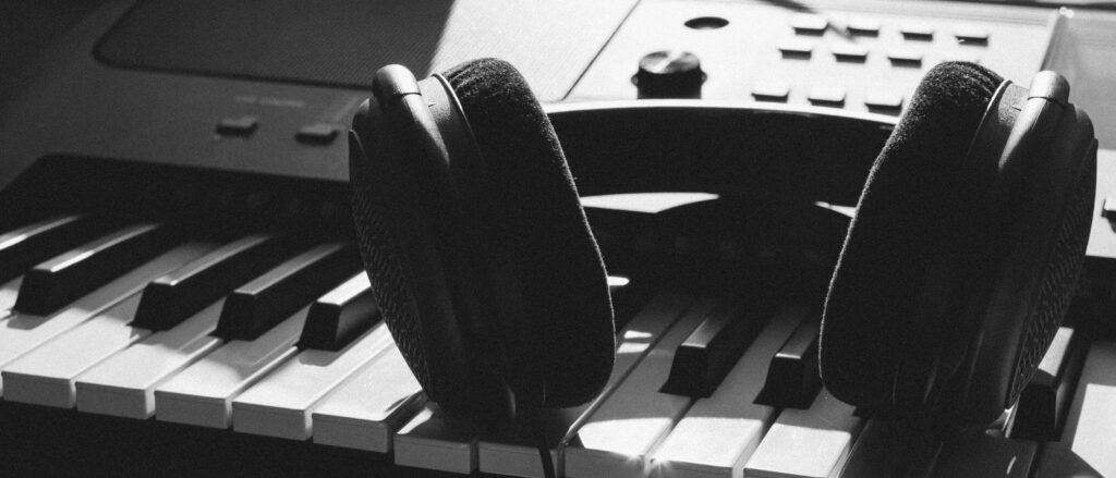 Close-up of headphones resting on piano keys, capturing the essence of music creation.