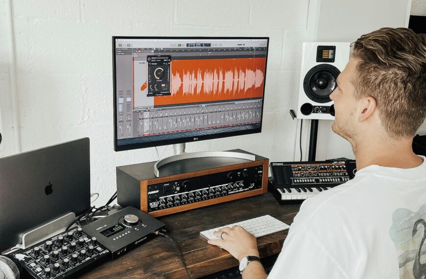Music producer using digital audio workstation in a modern home studio.